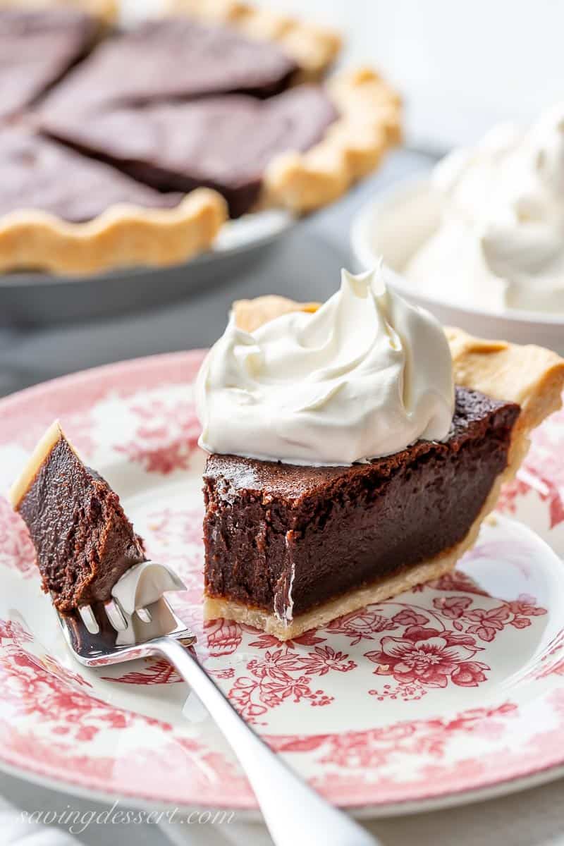 A partially eaten slice of chocolate pie topped with whipped cream