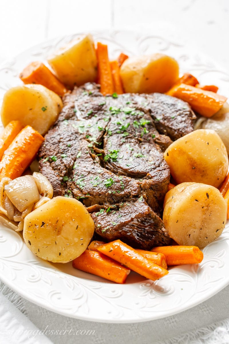 A platter with a slow cooker pot roast, potatoes and carrots