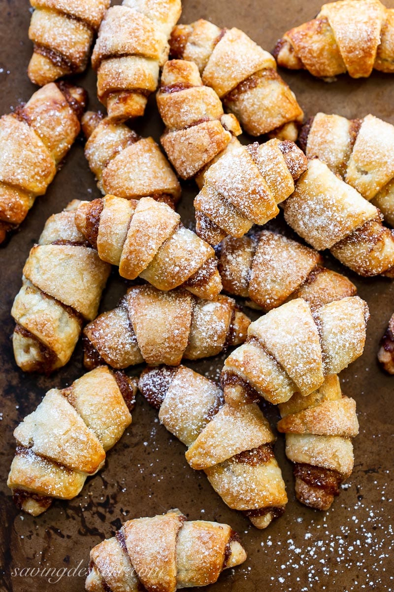 A cookie sheet covers with golden brown Rugelach cookies topped with powdered sugar