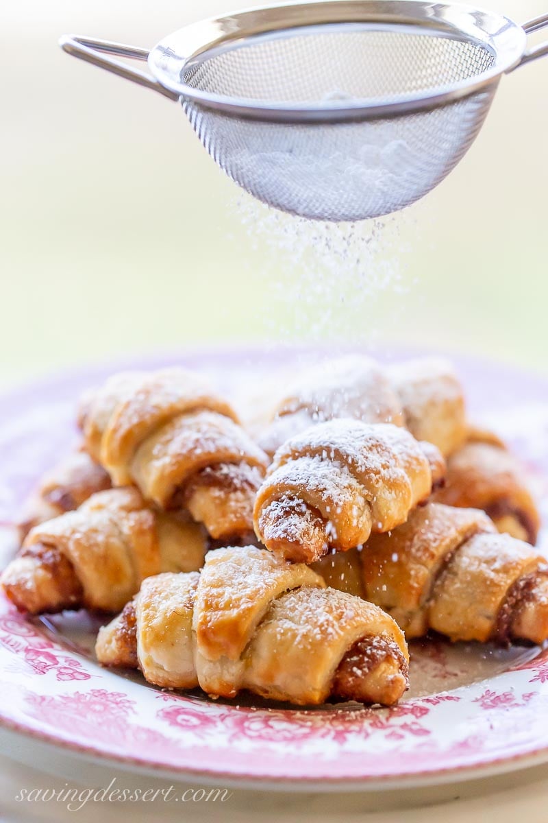 A plate of Rugelach cookies being sprinkled with powdered sugar
