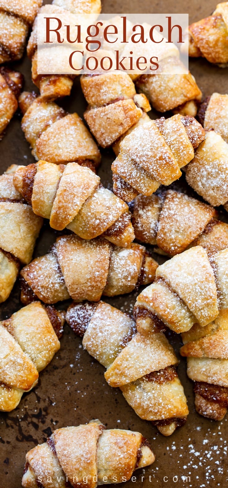 A cookie sheet with a stack of Rugelach cookies dusted with powdered sugar