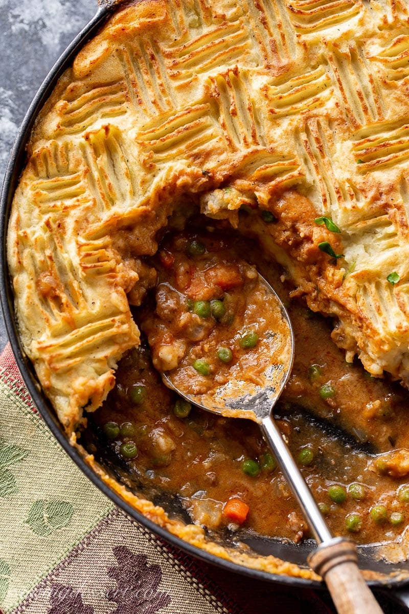 Cottage Pie topped with golden brown potatoes and a rich gravy with ground beef, carrots and peas