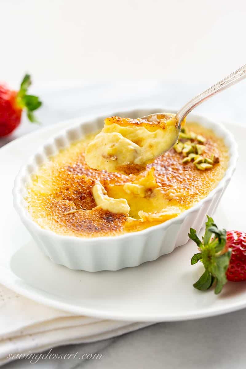 Crème Brûlée in a shallow ramekin with a scoop on a spoon