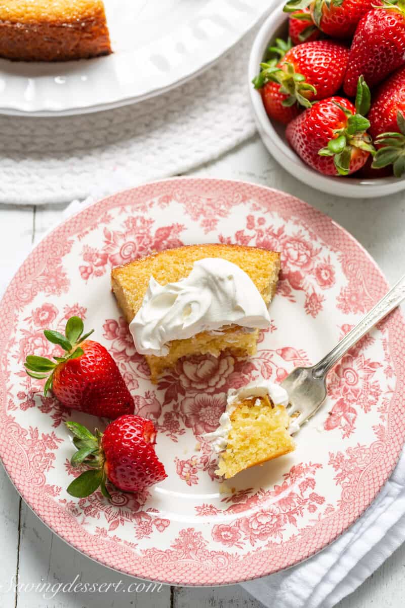 overhead view of a piece of cake on a plate topped with whipped cream and served with strawberries