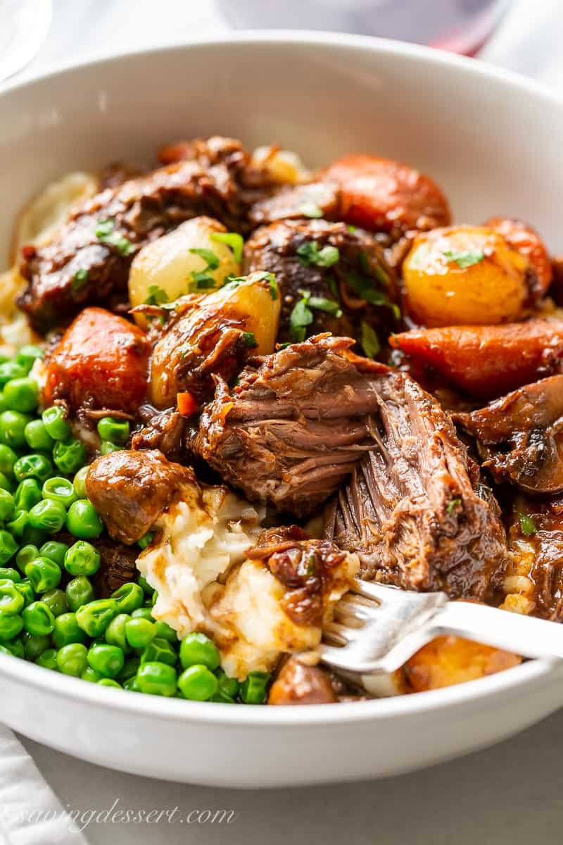 A bowl of Julia Child's Beef Bourguignon with a large chunk of beef cut in half