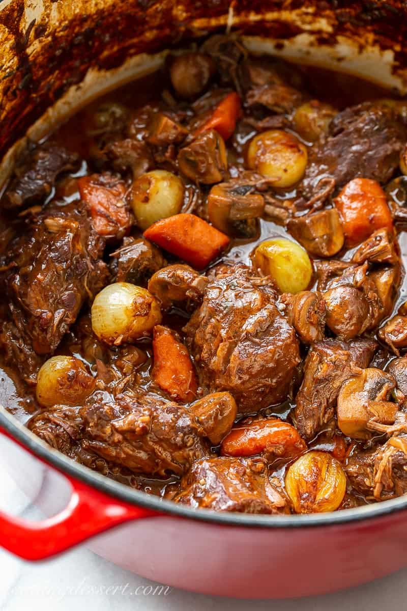 A Dutch oven filled with beef stew with onions and carrots