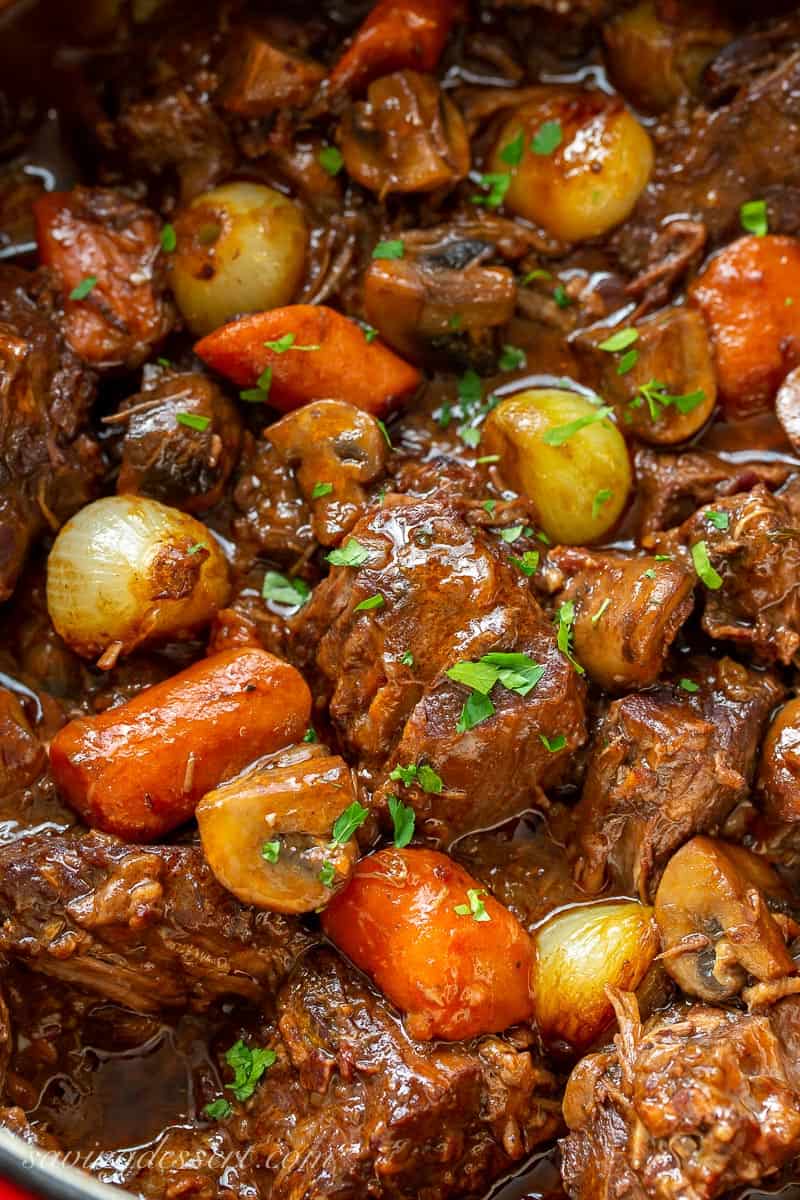 Close up of a pot of Julia Child's Beef Bourguignon with large chunks of beef, carrots, onions and mushrooms