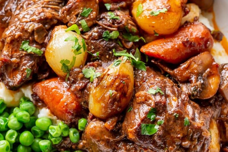 Class Beef Bourguignon served in a bowl over mashed potatoes and served with peas