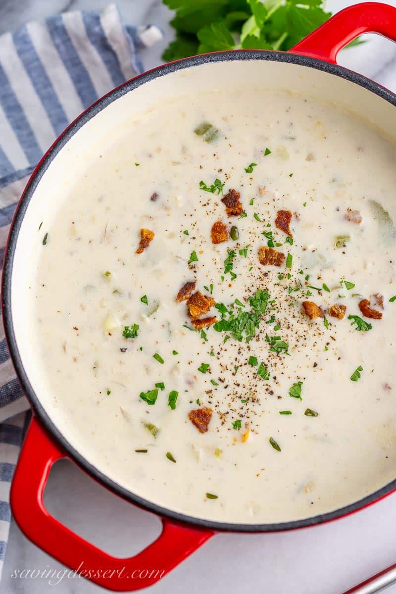 Overhead view of a pot of creamy soup garnished with bacon bits and parsley