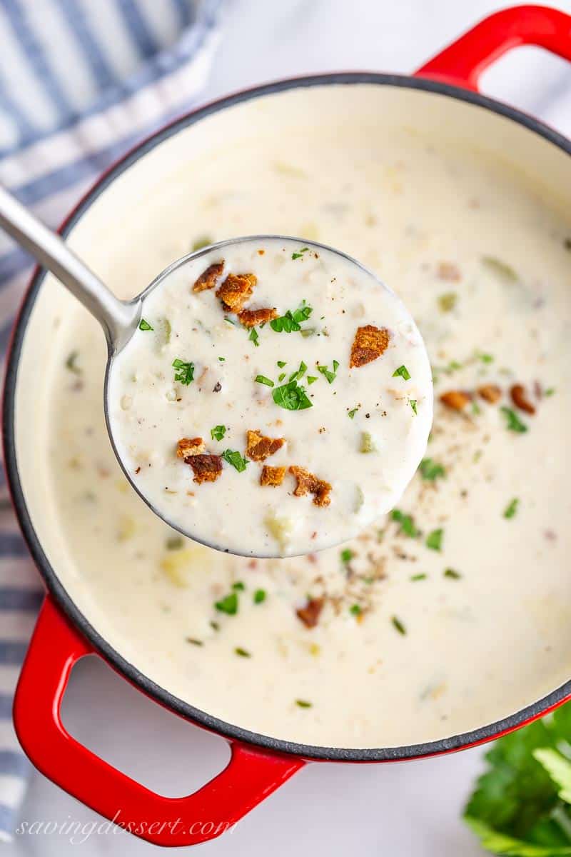 A ladle of creamy potato and clam chowder with bacon