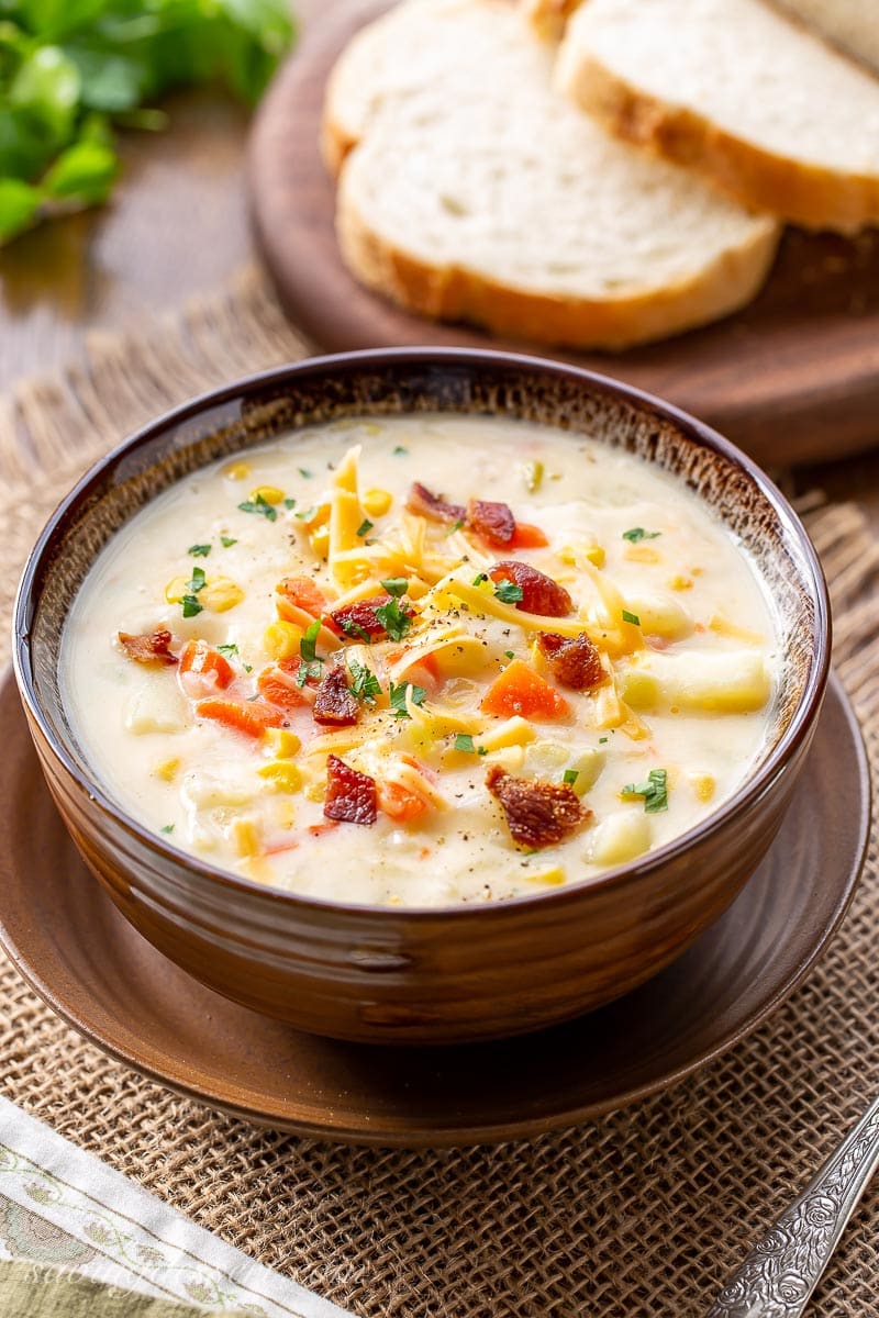 A bowl of creamy, cheesy corn and potato chowder garnished with cheese and bacon