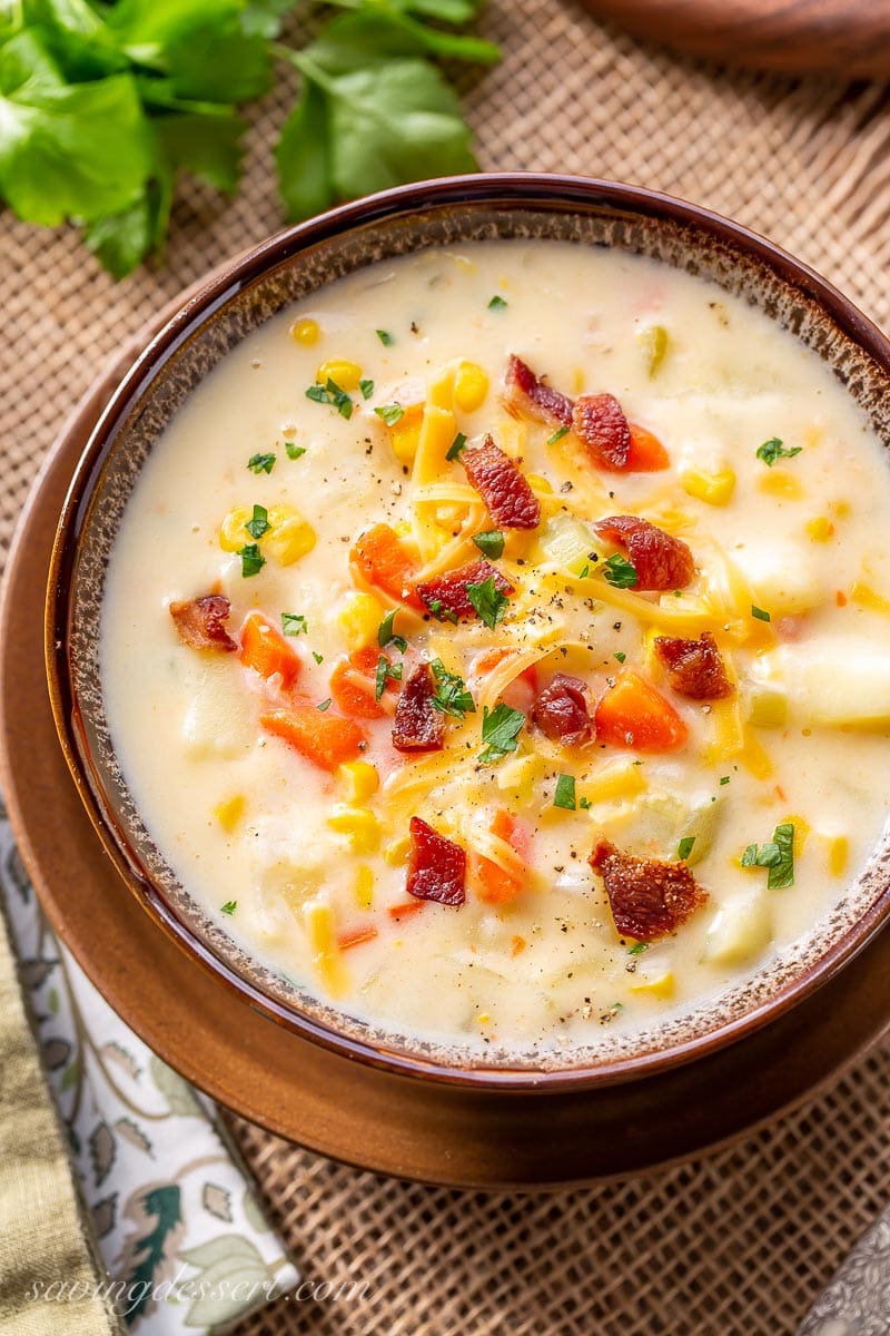 A hearty bowl of corn and potato chowder garnished with bacon and parsley
