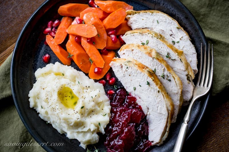 An overhead view of a plate of turkey, potatoes, carrots and cranberry sauce