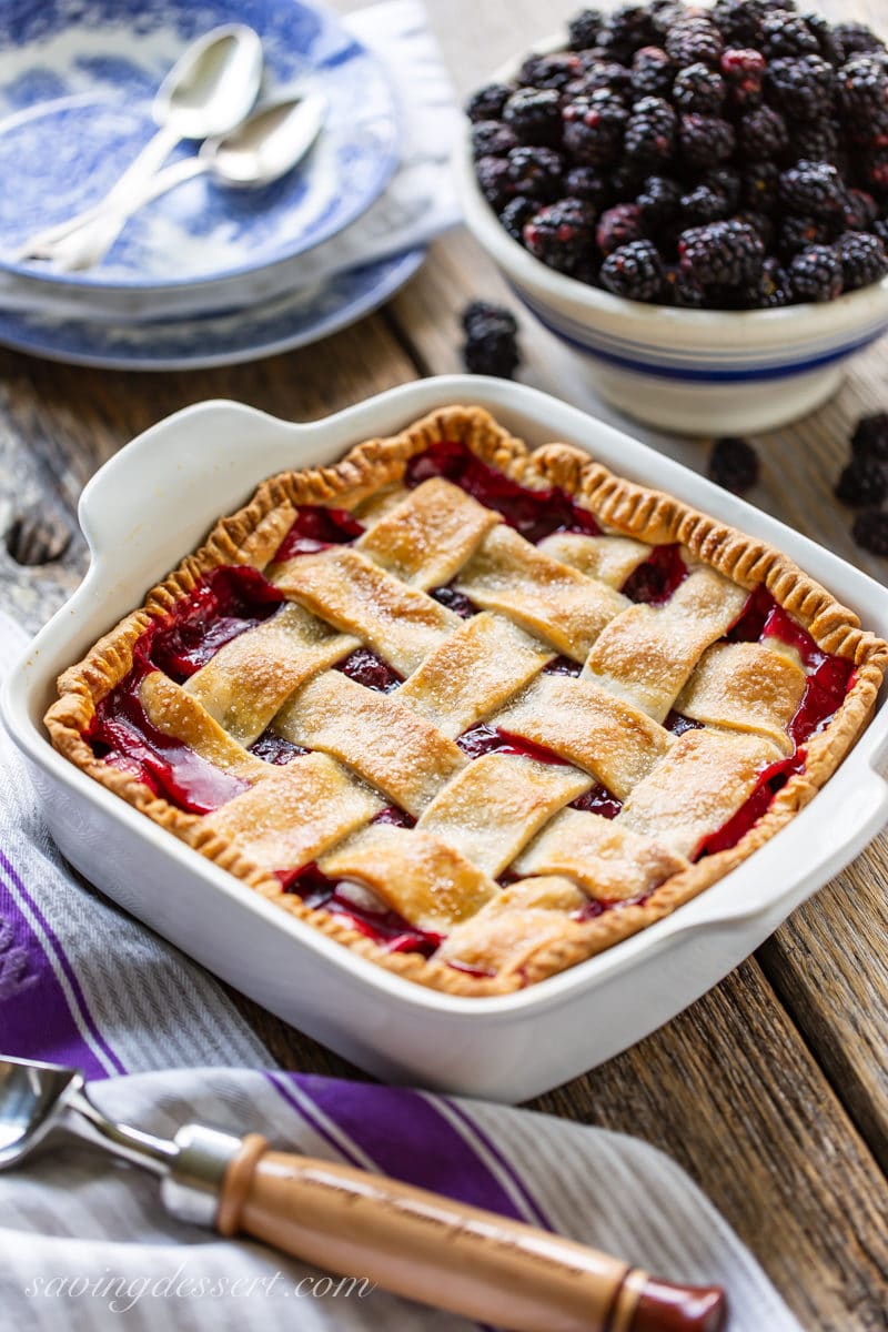 An old-fashioned blackberry cobbler with a lattice top and a bowl of fresh blackberries