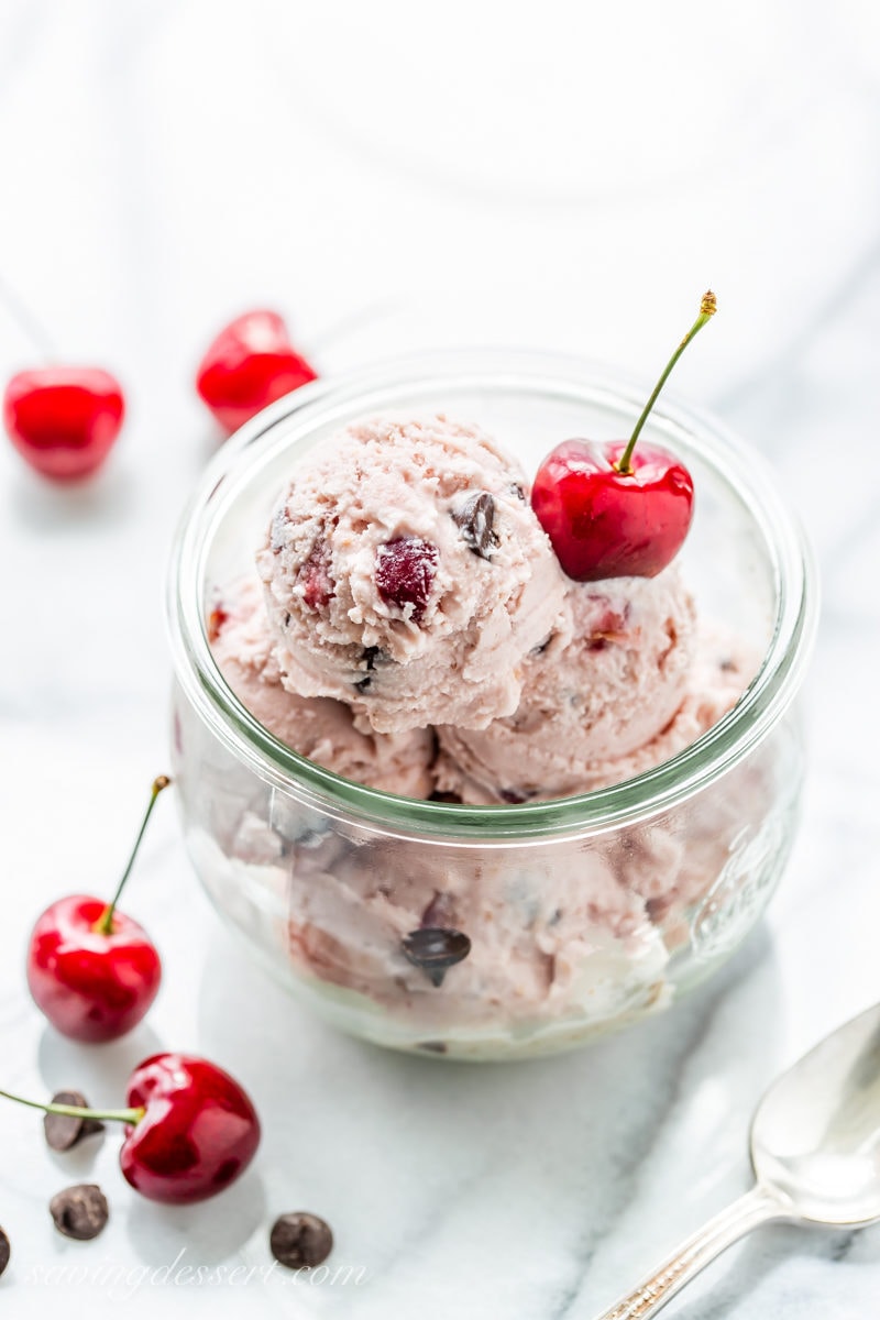 A jar filled with scoops of fresh cherry ice cream with dark chocolate chips