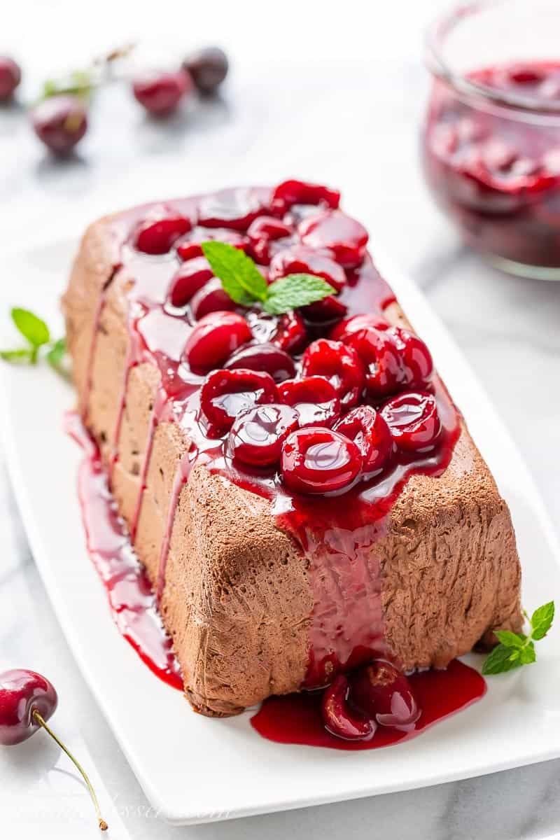 Chocolate Marquise on a platter topped with mint and fresh cherry sauce