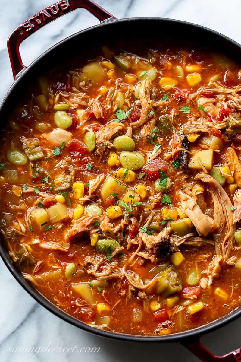 An overhead view of a soup pot filled with Brunswick Stew with corn, okra, lima beans, tomatoes and smoked meats