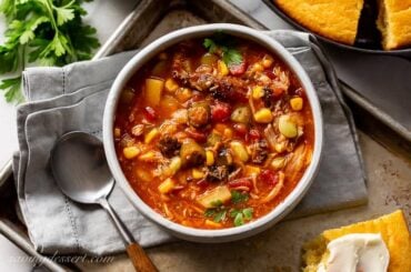 A bowl of brunswick stew on a baking tray with cornbread on the side