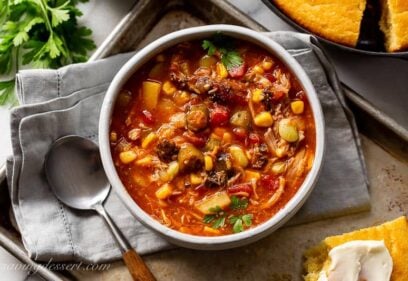 A bowl of brunswick stew on a baking tray with cornbread on the side