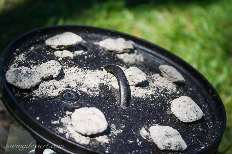 an outdoor cast iron Dutch Oven with hot coals on the lid