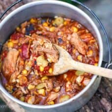 A small camping pot with Brunswick Stew and a wooden spoon