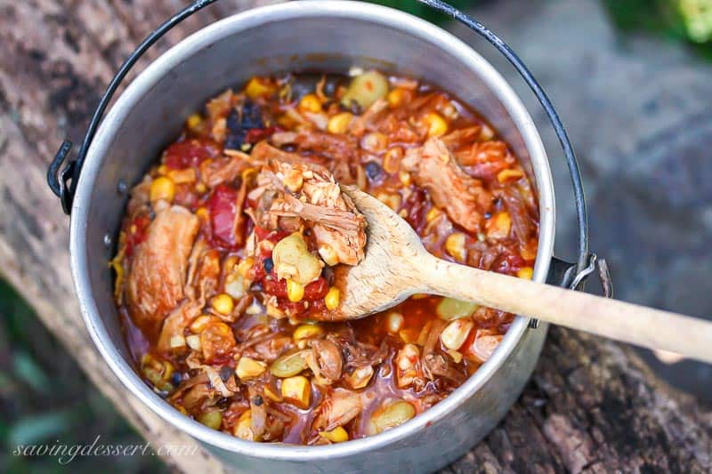 A small camping pot with Brunswick Stew and a wooden spoon