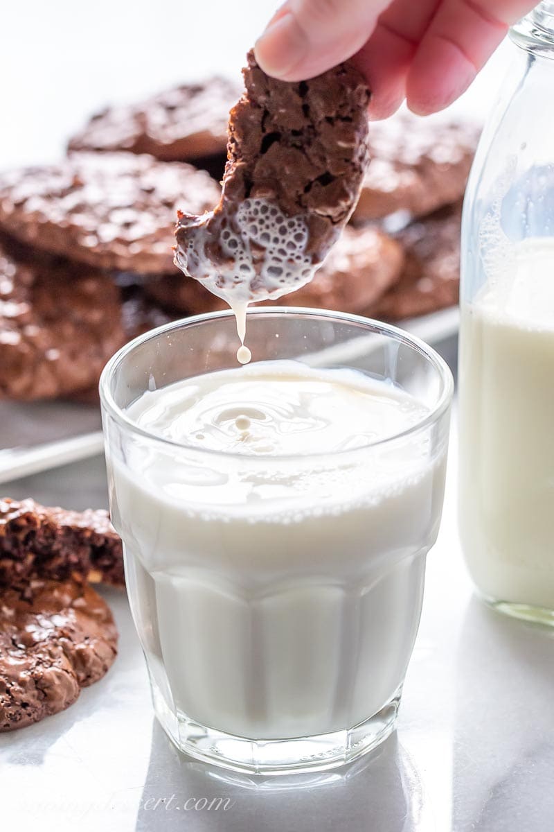 A chocolate cookie dunked in a glass of milk