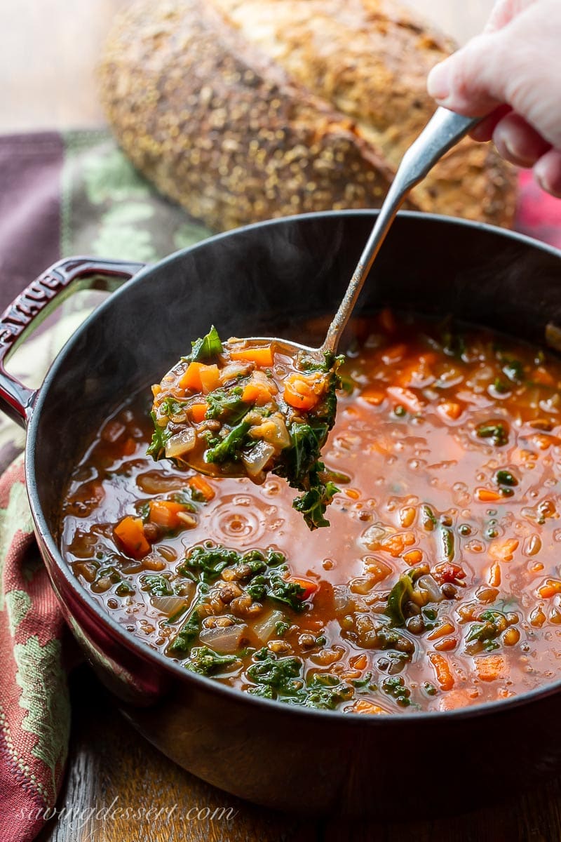 A pot of hot lentil soup being ladled into a bowl