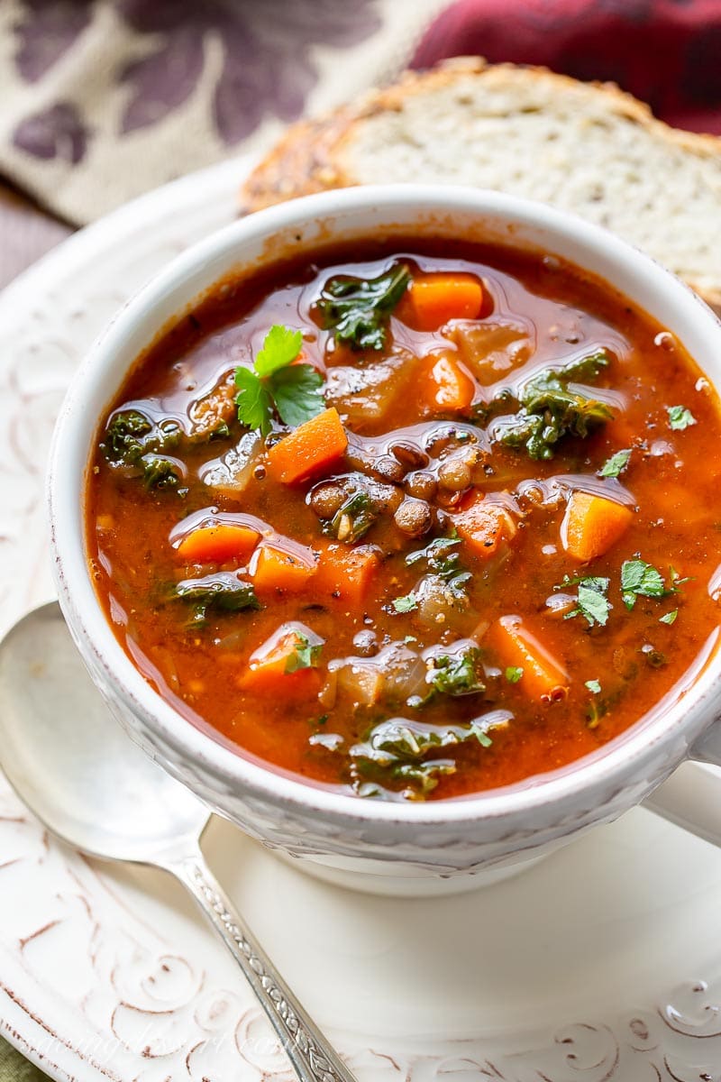 A bowl of soup with carrots, lentils and kale