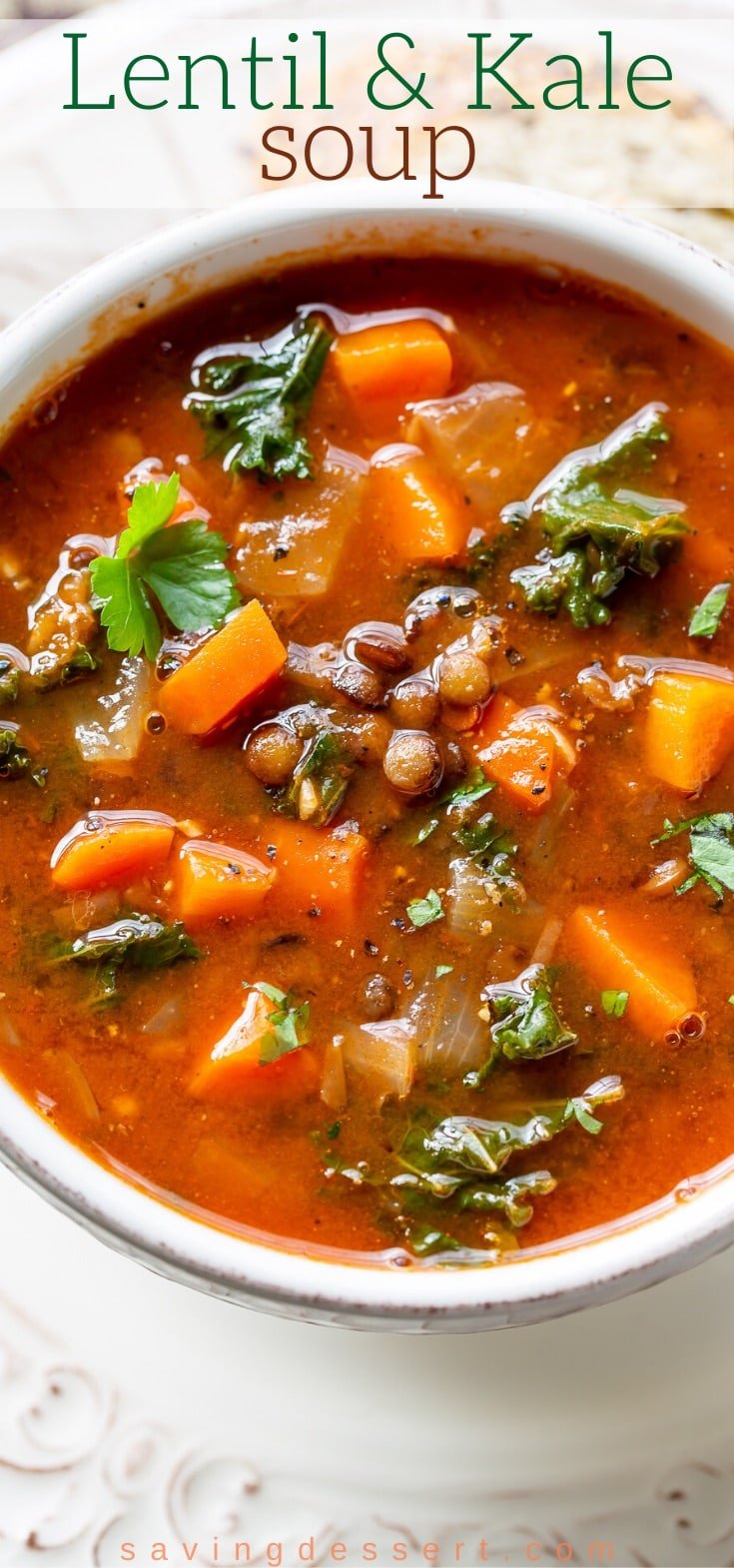 An overhead view of a rich bowl of lentil soup with kale, carrots and onions