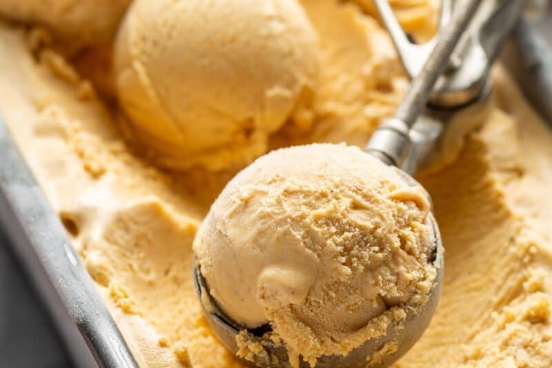 Closeup of a loaf pan filled with scoops of pumpkin ice cream.