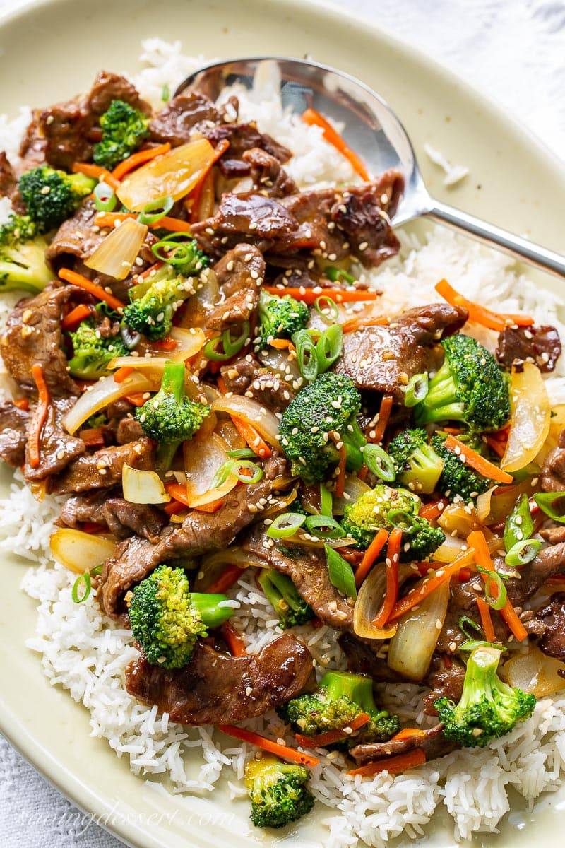 A platter with rice, beef, broccoli, onions and carrots