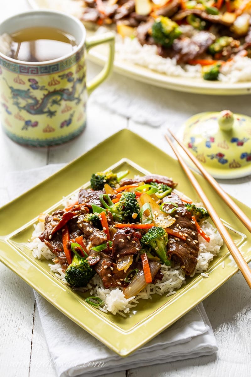 A plate with beef and broccoli stir-fry served over rice with a cup of tea