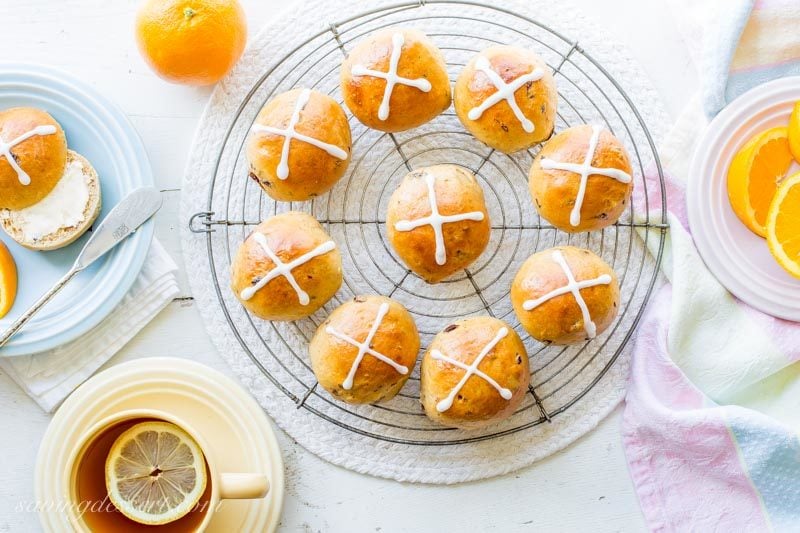 homemade hot cross buns with orange slices and a cup of tea