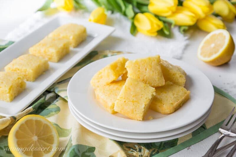 lemon blondies sliced with a sliced fresh lemon and yellow tulips