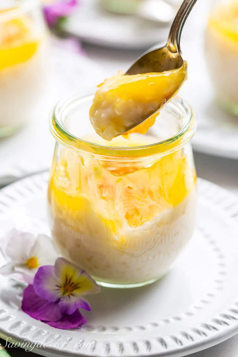A spoon scooping out coconut tapioca pudding topped with lemon curd.