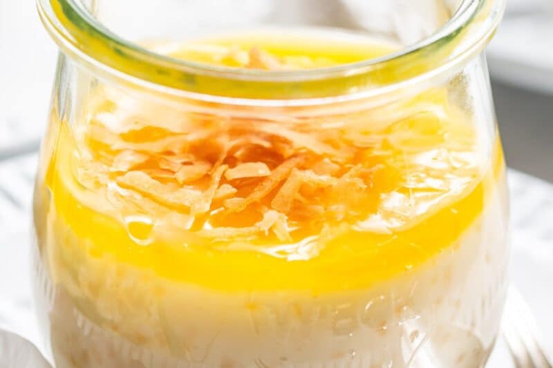 A small jar filled with coconut tapioca pudding with lemon curd and toasted coconut on top.