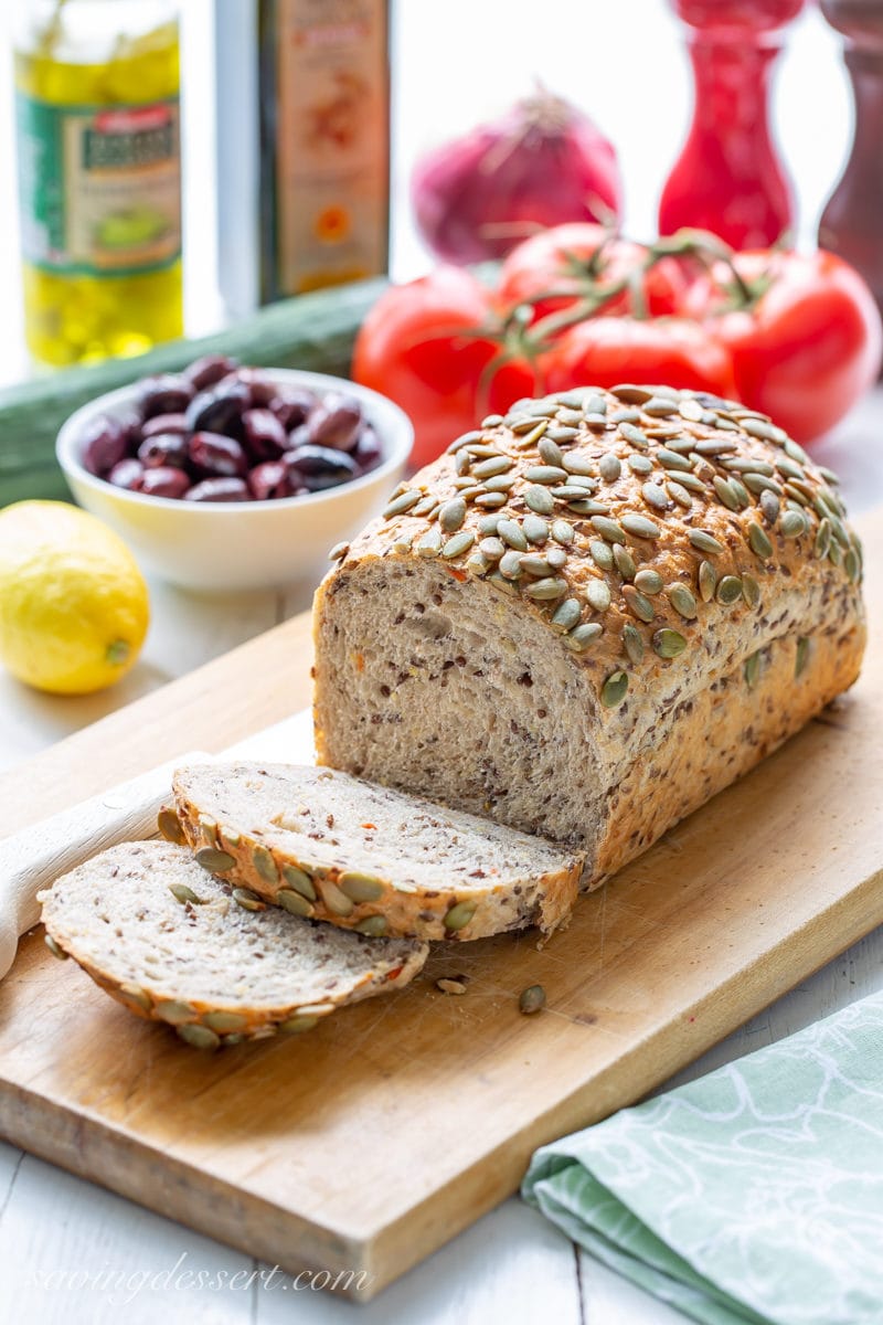 A sliced loaf of Wegman's Marathon Bread with olives, tomatoes and cucumbers