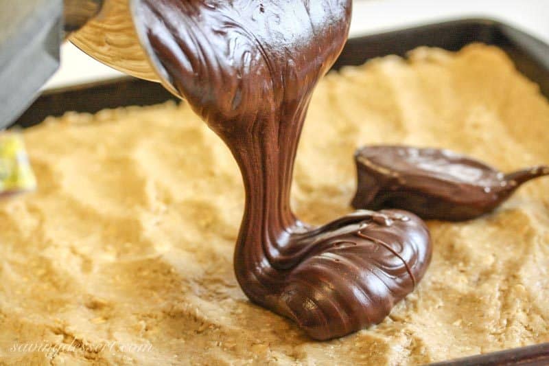 A pan of cookie dough being drizzle with a warm, silky chocolate mixture