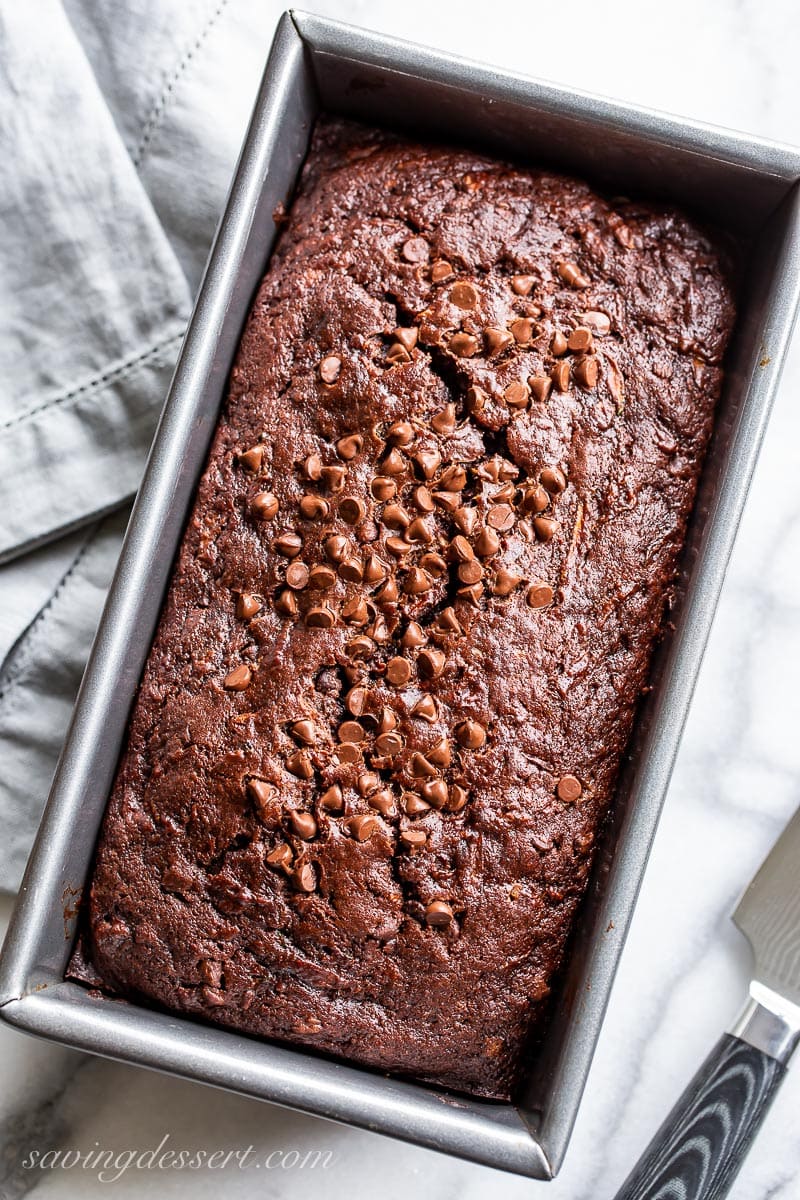 An overhead view of a loaf pan filled with chocolate zucchini bread topped with mini chocolate chips