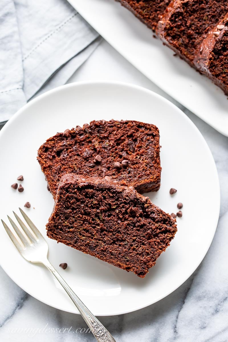 Two slices of chocolate zucchini bread on a plate with a fork