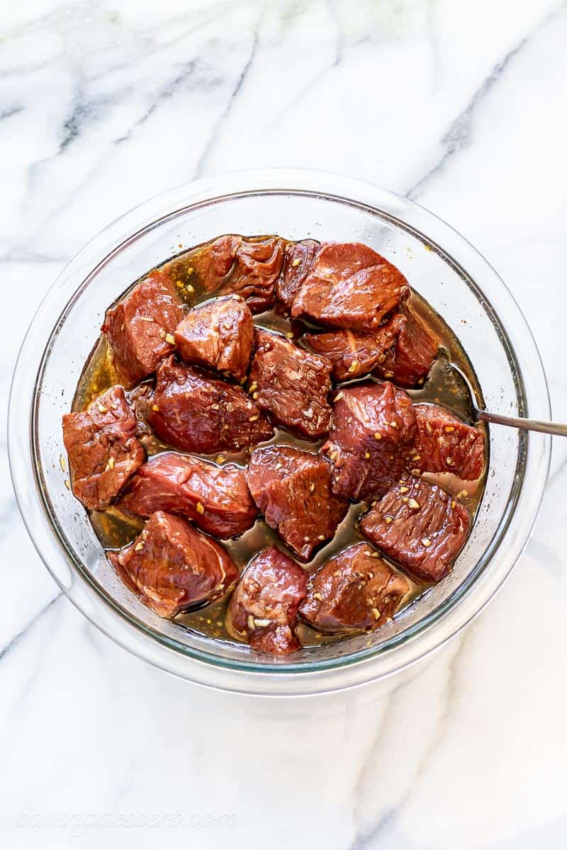 A bowl of cubed beef in a marinade