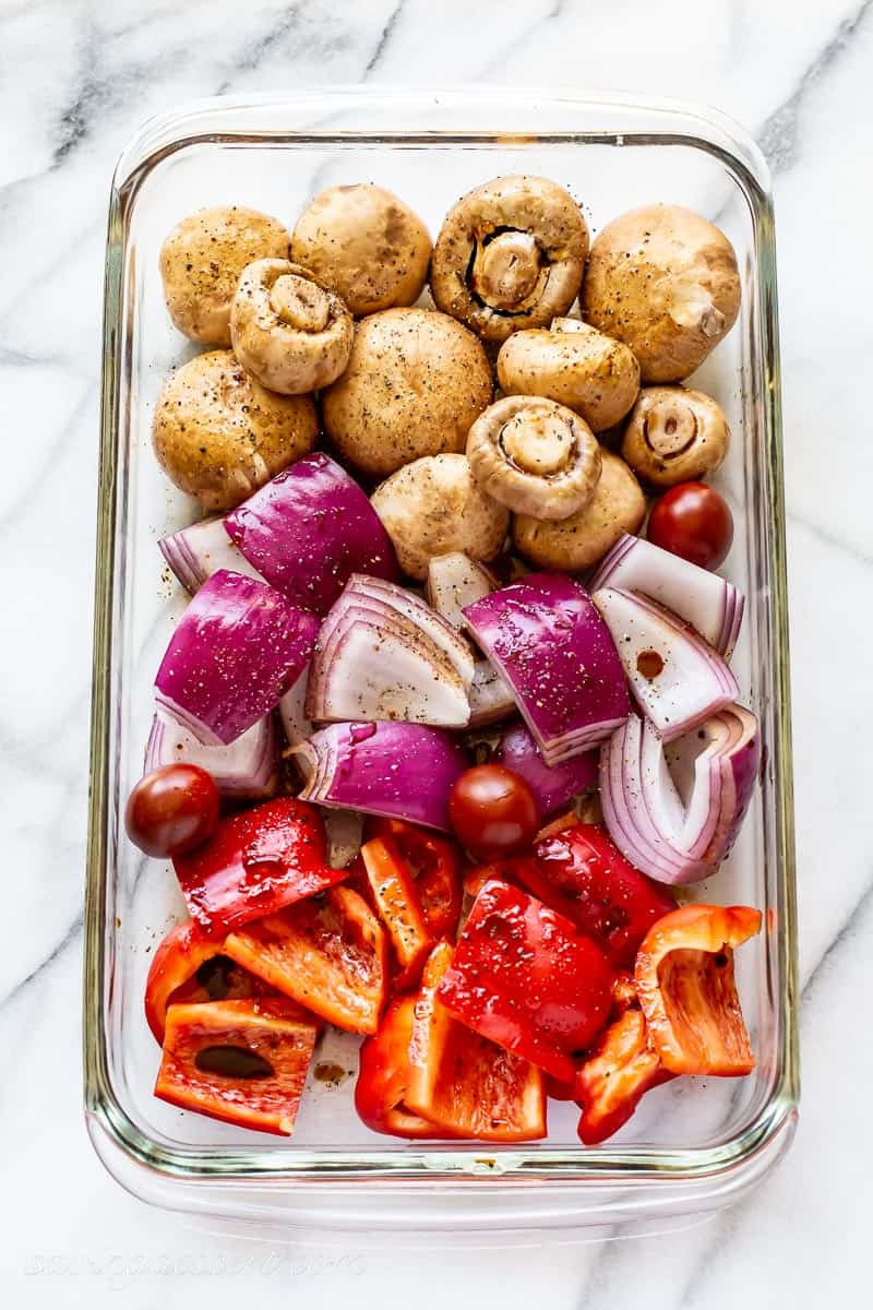 A glass pan with mushrooms onions and red pepper cubes