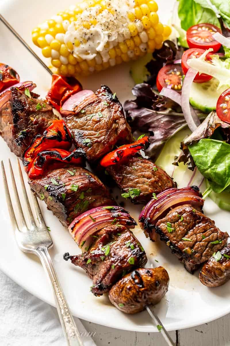 An overhead of a plate with steak kabobs, salad and corn