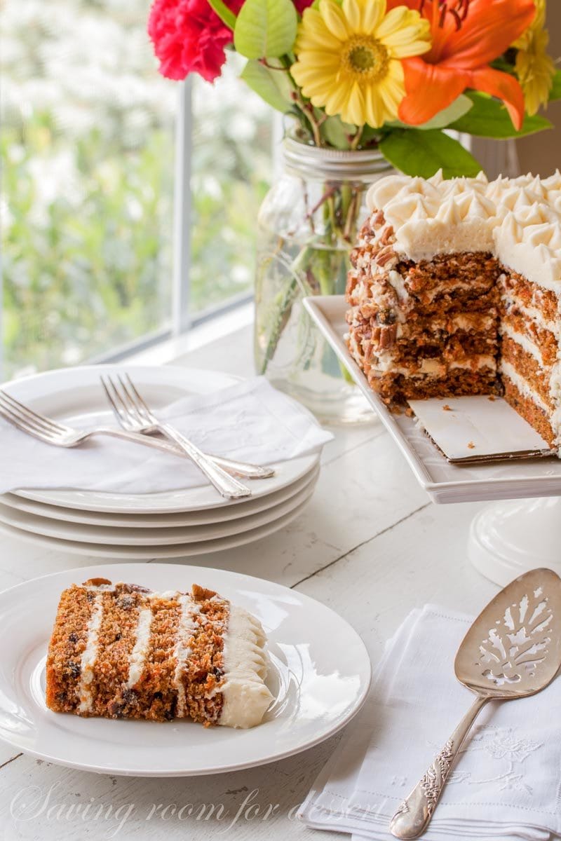 a slice of carrot cake with toasted pecans and cream cheese icing on a plate