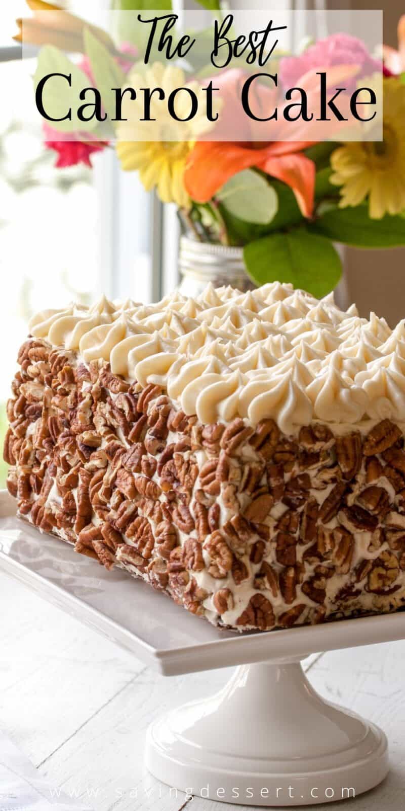 A rectangle shaped carrot cake covered in toasted pecans on a cake stand