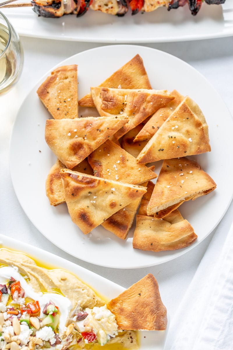 A plate of homemade whole wheat pita chips seasoned with sea salt, oregano and black pepper