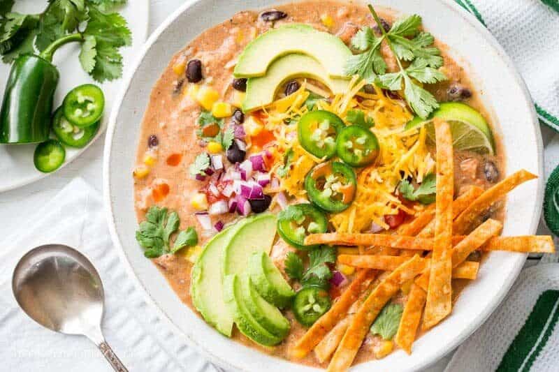 Cream Taco Soup with chicken and topped with avocado, cheese and lime