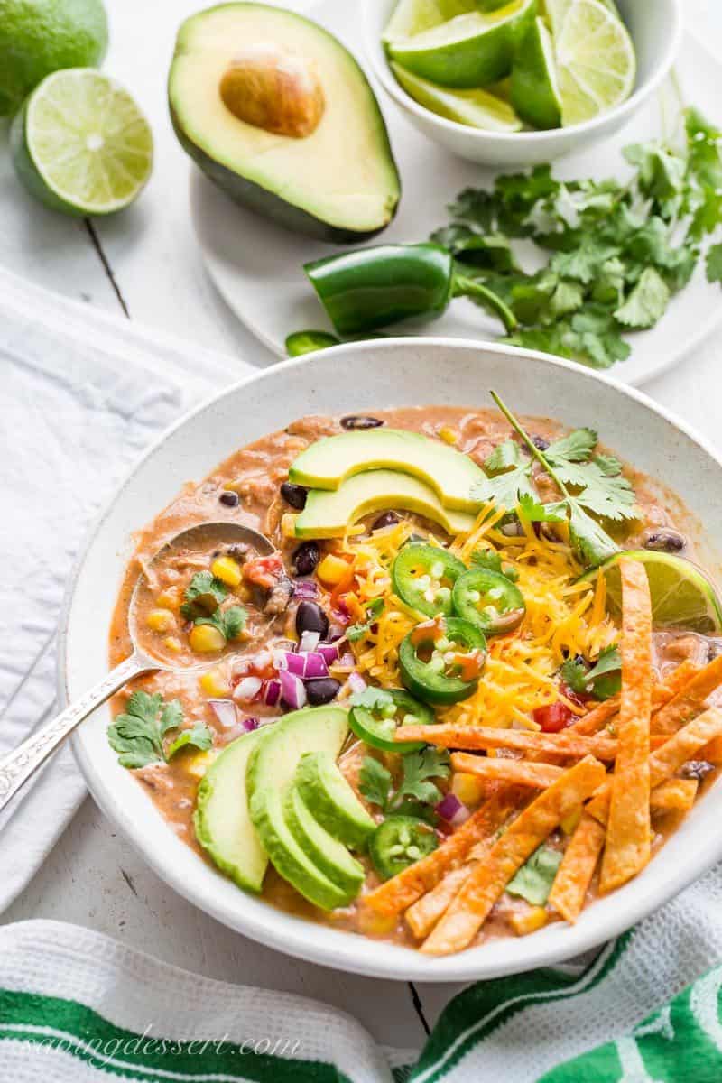 Cream Taco Soup with chicken and topped with avocado, cheese and lime