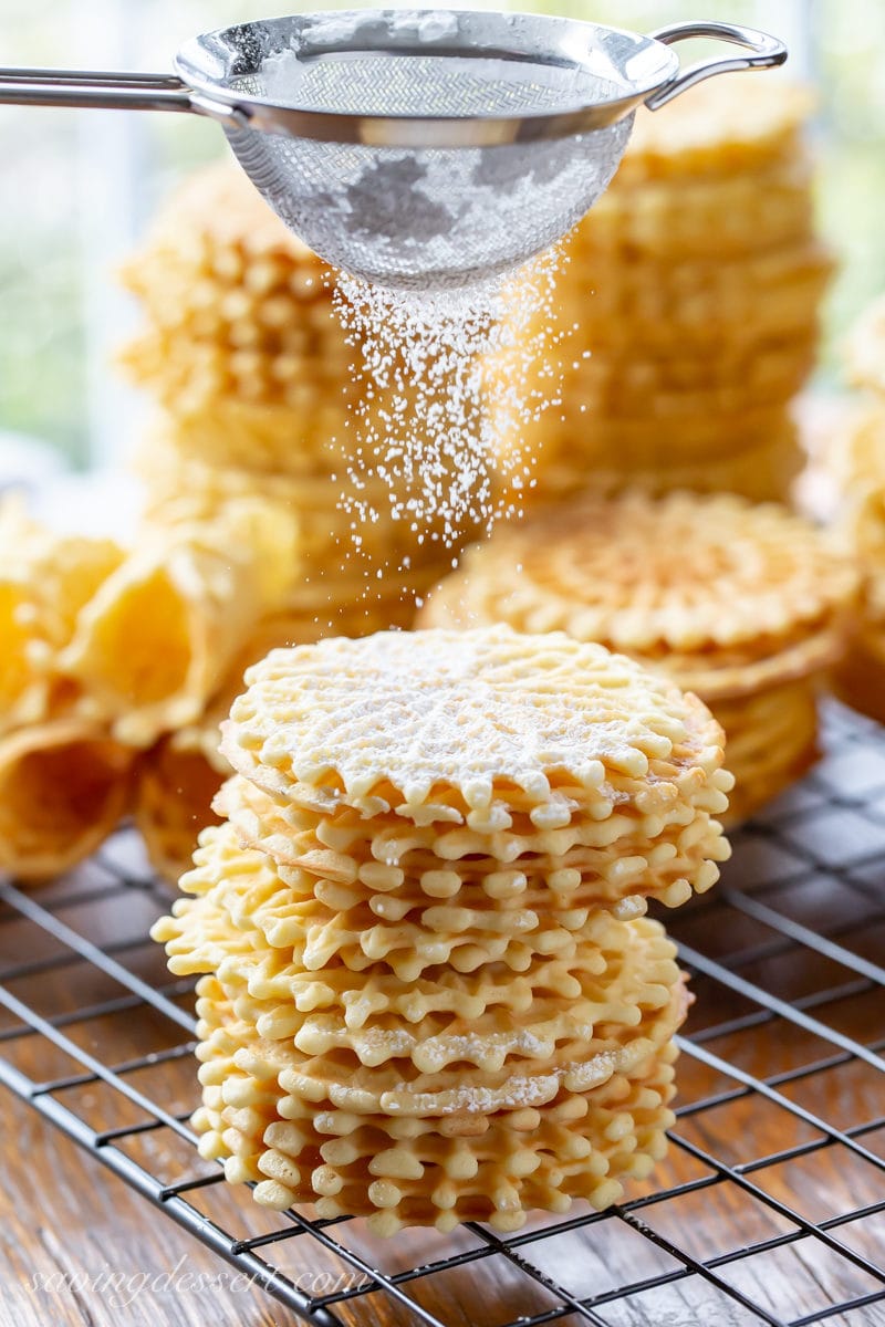 A stack of pizzelle cookies dusted with powdered sugar
